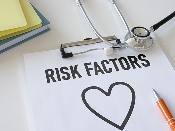 Clipboard on desktop with stethoscope and a heart shaped drawing that says, "Risk Factors" above the heart