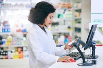 Let me put in a order for this product. a pharmacist working on a computer in a pharmacy.