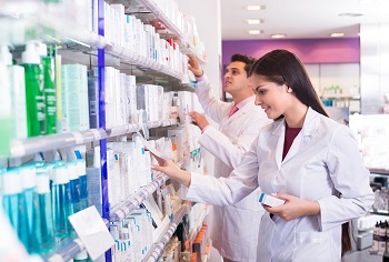 Male and Female pharmacy technicians pulling drugs from the shelves.