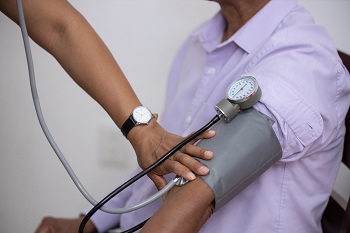 Health practitioner manually taking patient's blood pressure using a cuff and stethoscope. 
