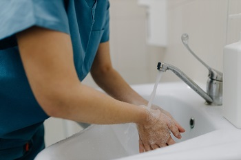 Female medical worker washing her hands meticulously with water.