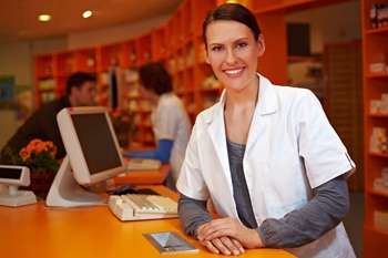 Smiling Pharmacy staff member leaning on counter.